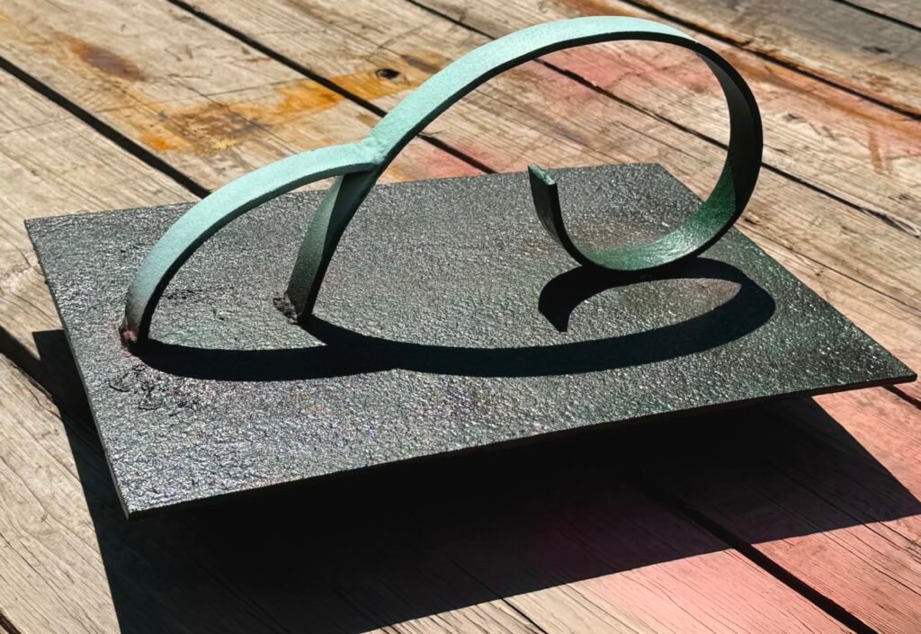 Fibo Dub by Joe Kyte, abstract metal sculpture formed from a continuous looping curve on a rectangular base